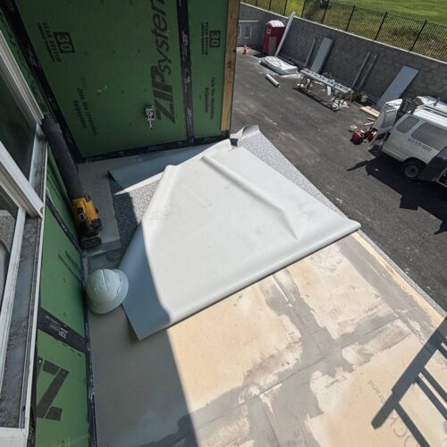 A construction site with a balcony on which a sheet of material, a helmet, and a drill are lying