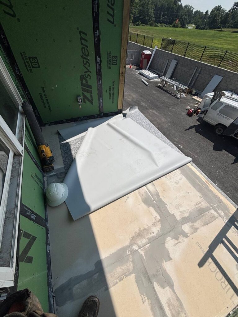 A construction site with a balcony on which a sheet of material, a helmet, and a drill are lying